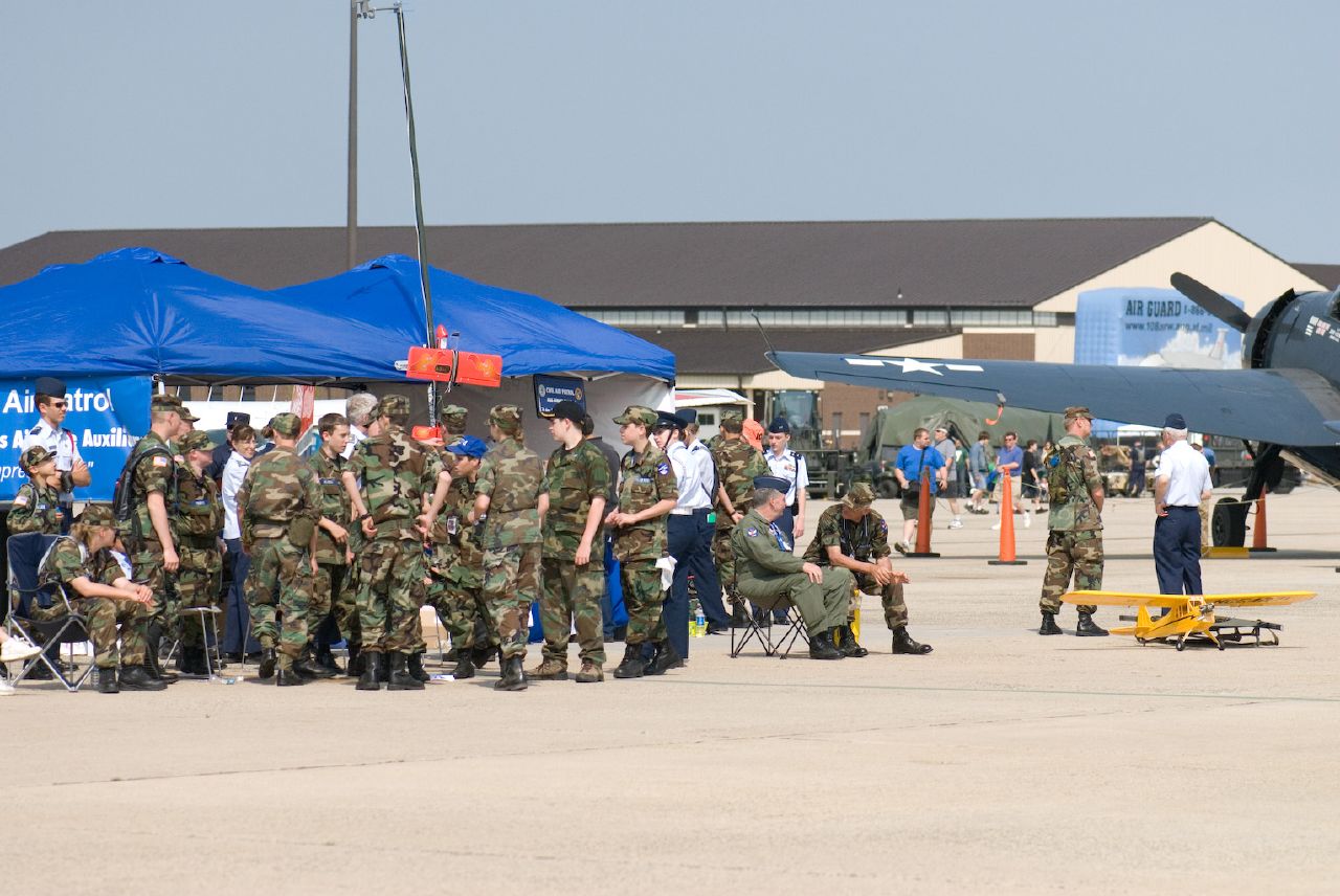 soldiers in uniform confering with small aircraft near some tents