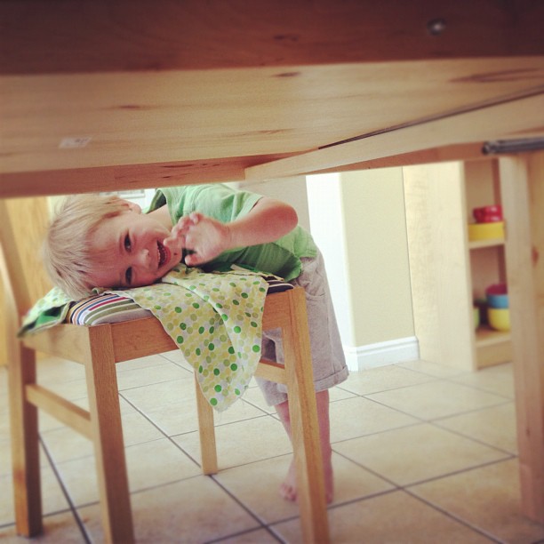 a toddler sitting at a wooden table eating