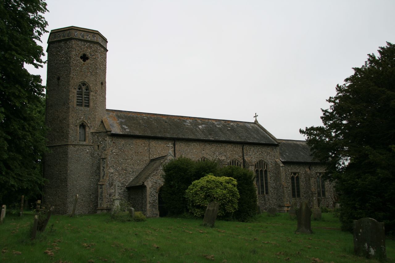 a church with a tall tower and grass in front
