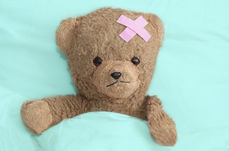 a small teddy bear with a pink tape on its head