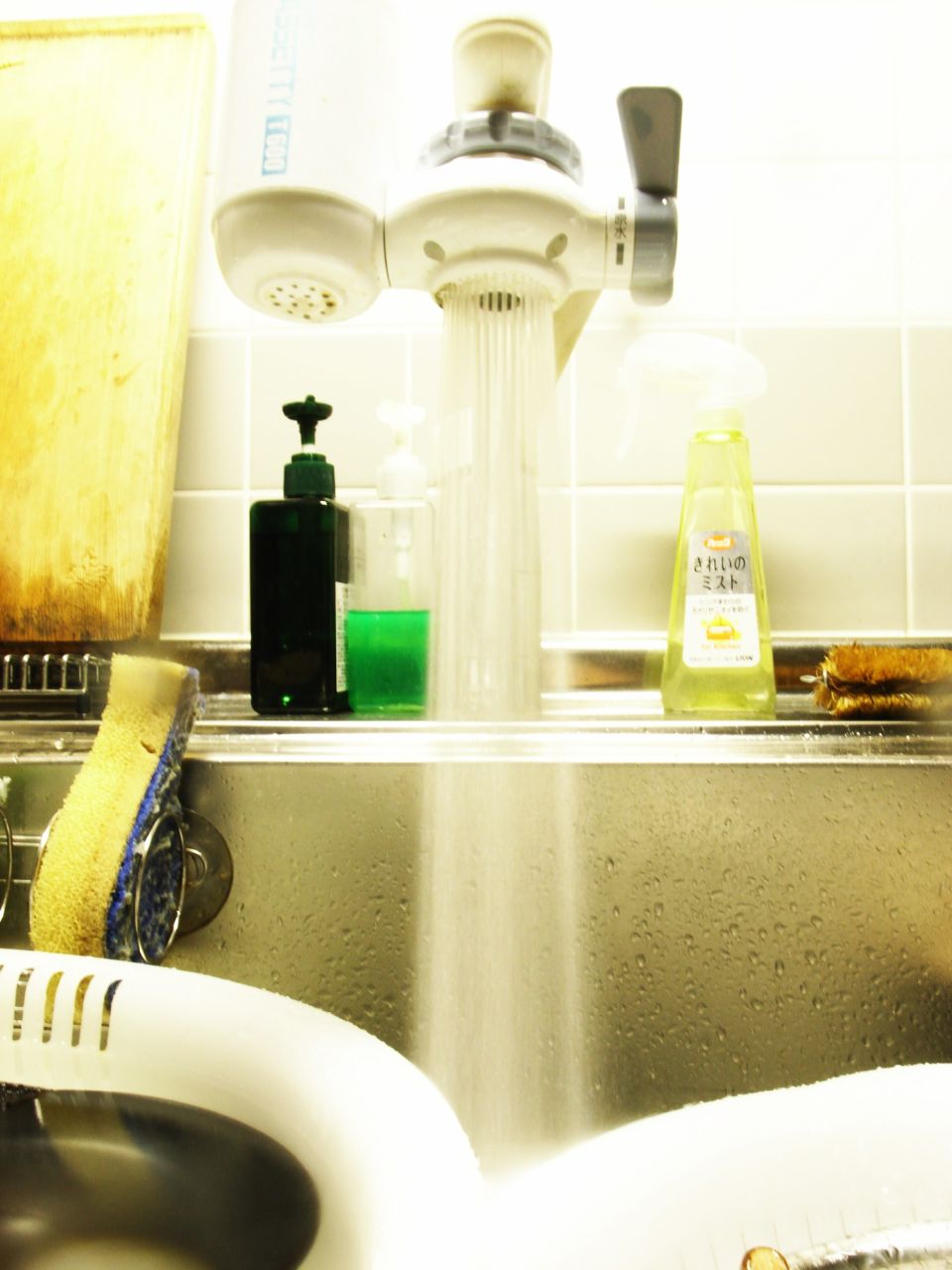 several soaps, water and toothbrushes are in a bathroom sink