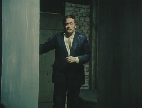 man standing in doorway with jacket over his chest
