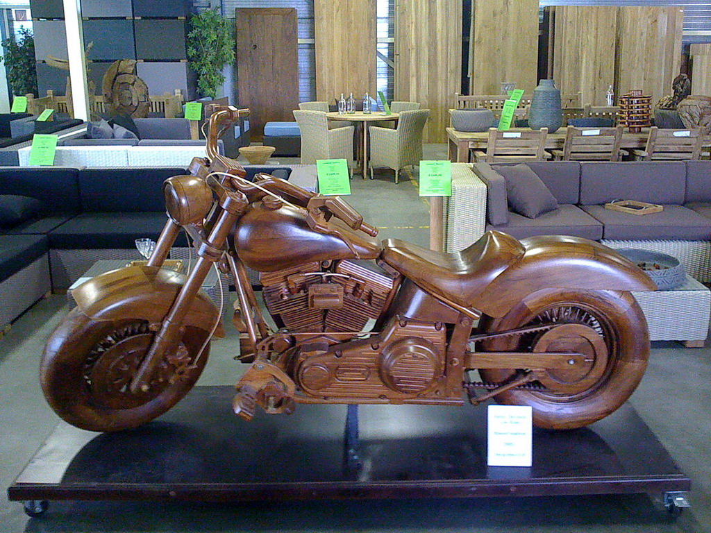 a wooden motorcycle sits on a black stand