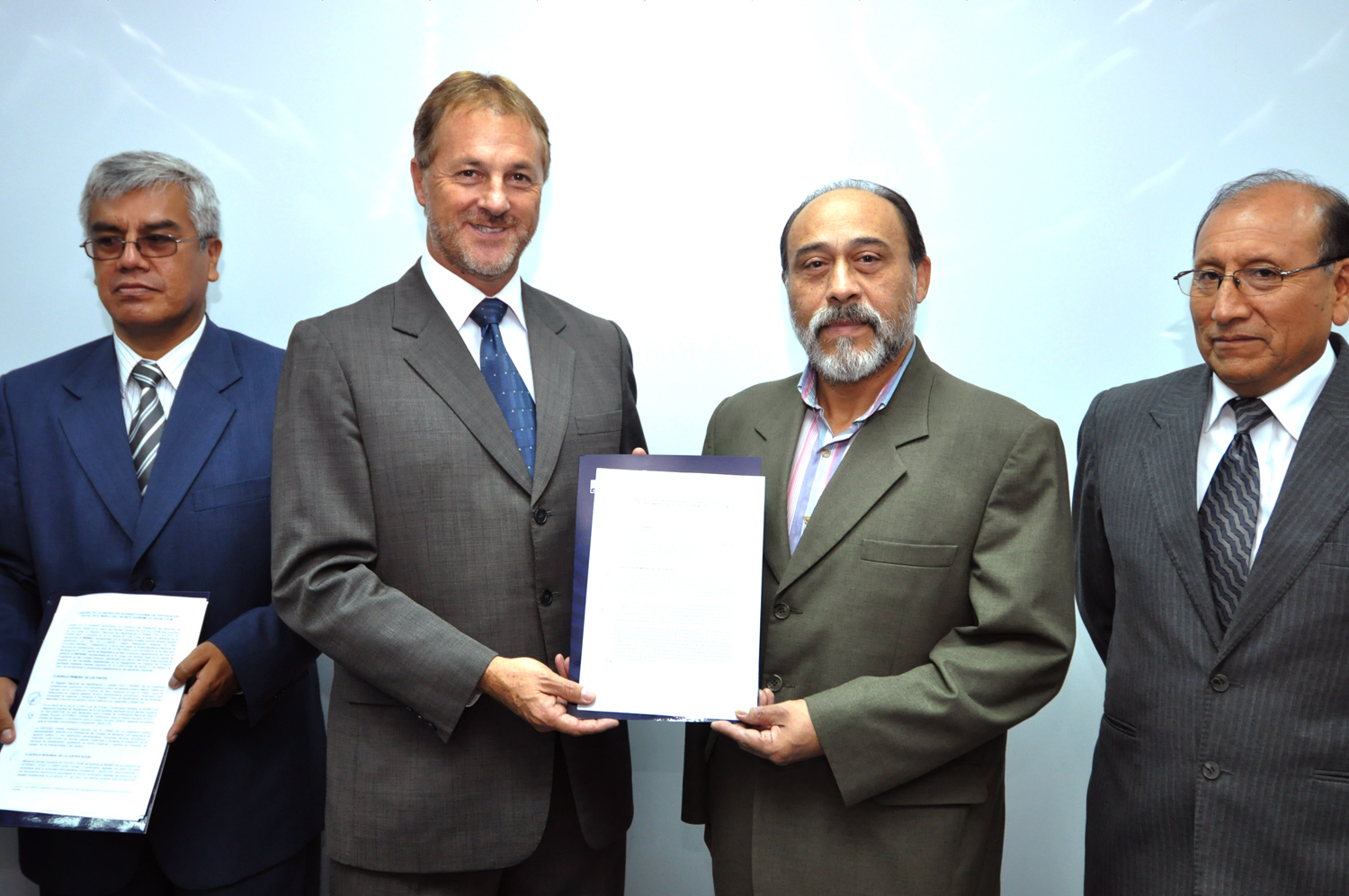 four business men holding two sheets of paper