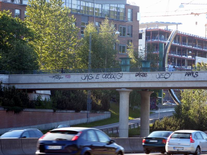 a bridge with graffiti above a street that is very busy