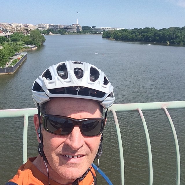 a man in sunglasses is wearing an orange top and helmet