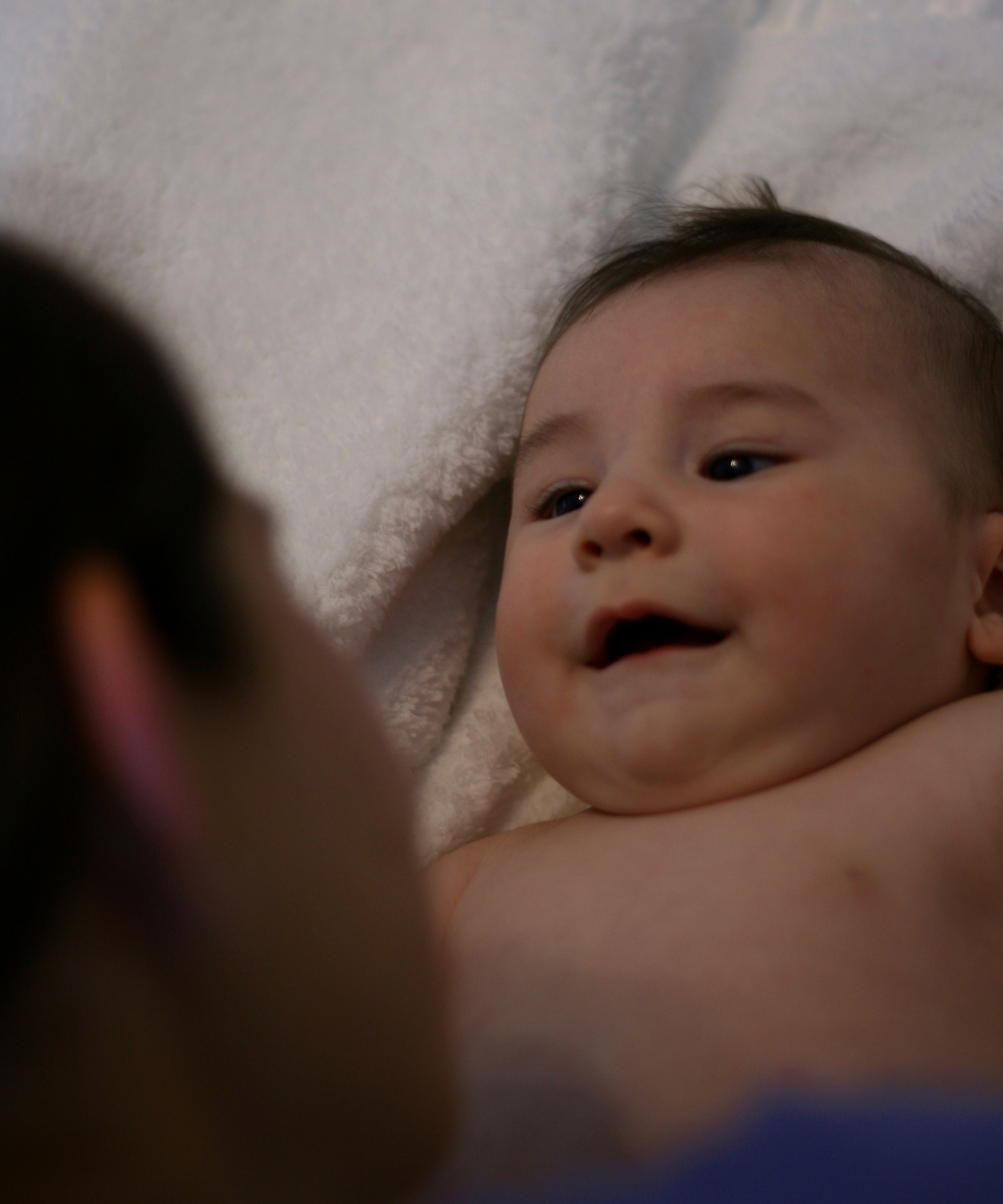 a baby laying in the bed with its face partially hidden behind white sheets