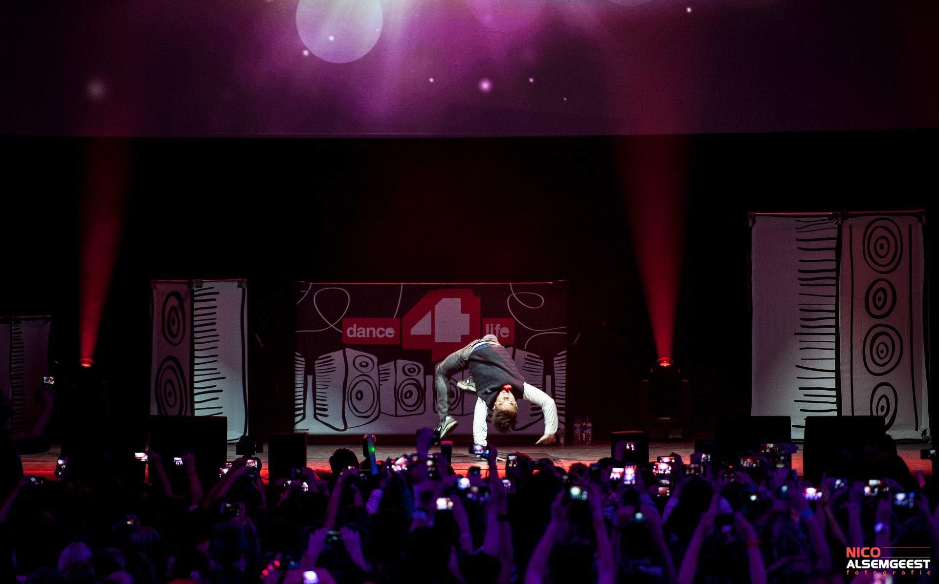 an energetic man in white shirt performing on stage