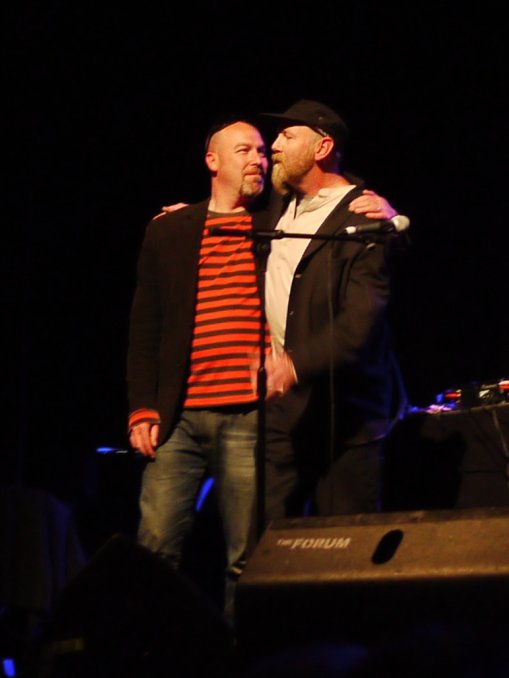 the man is hugging the other guy in front of a microphone