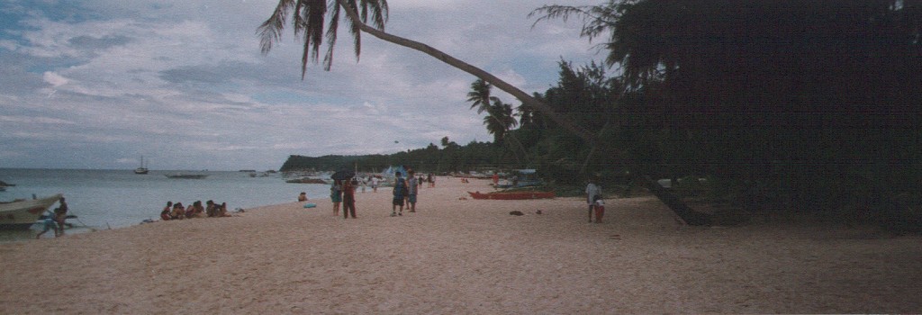 people walking on the beach with boats in the water