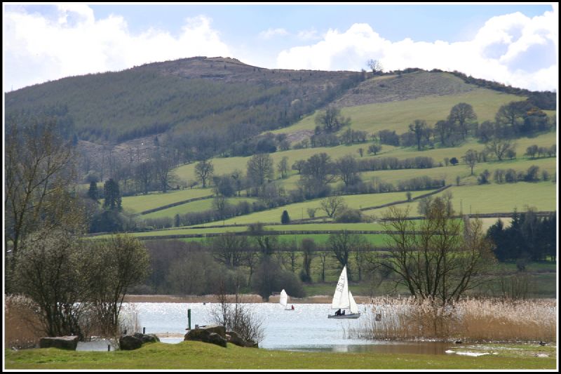 two sailboats in a lake surrounded by green mountains