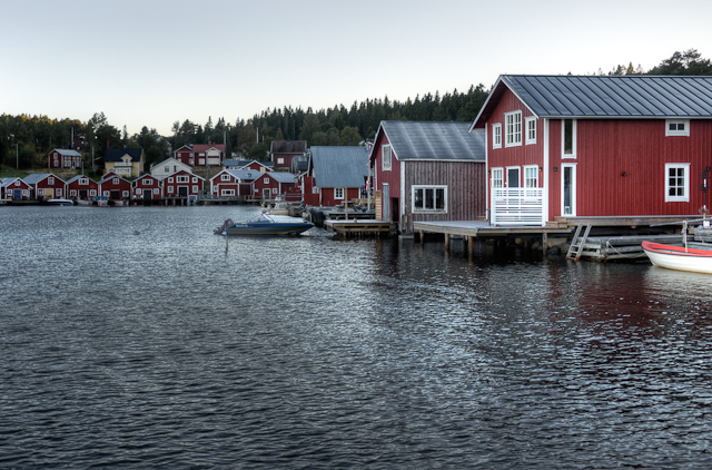 a small dock area with red colored houses along it