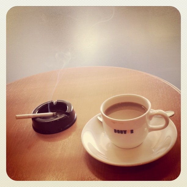 a cup of coffee is sitting on the table next to a smoke stick
