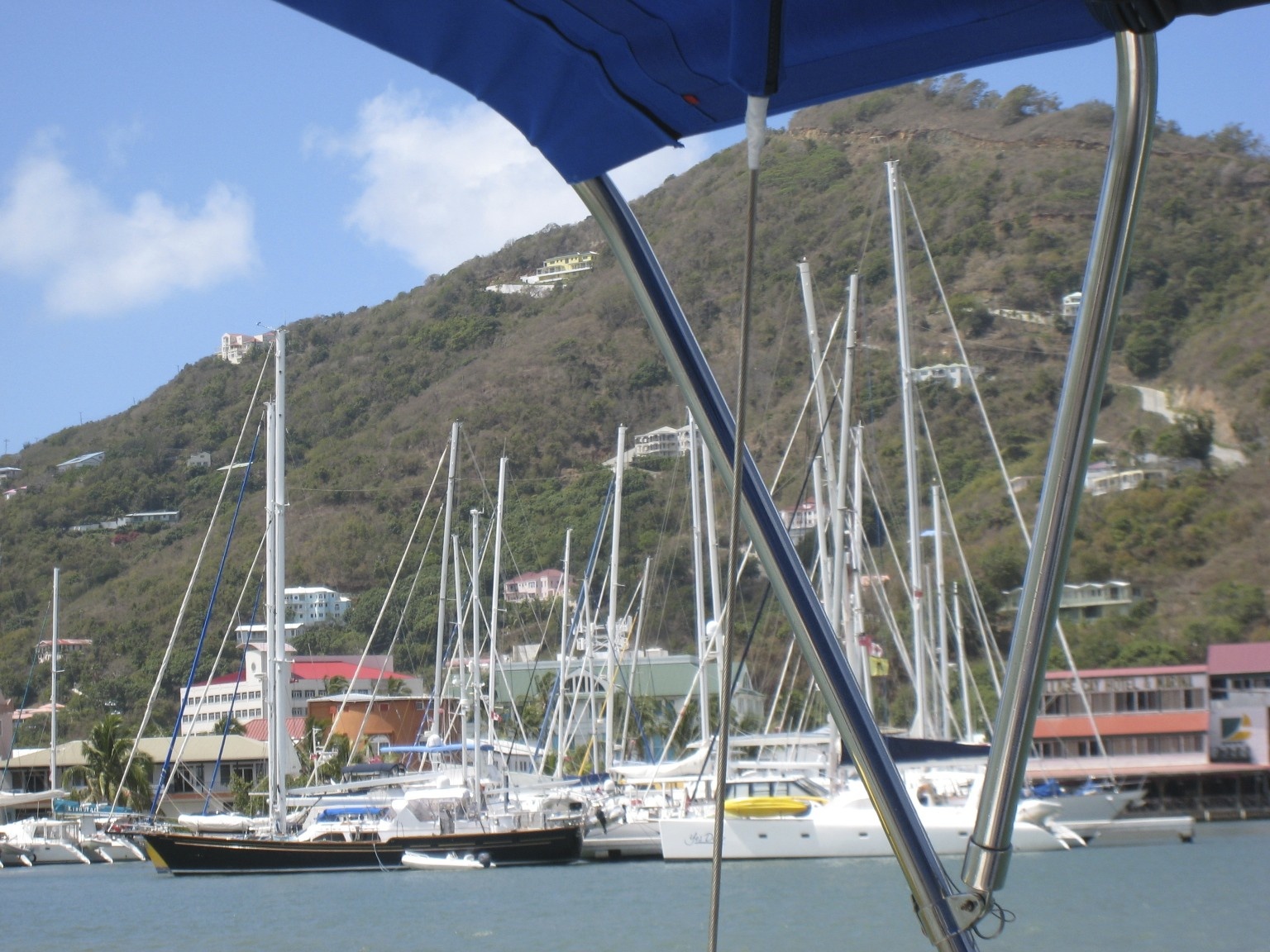 a dock full of white boats in front of a hill