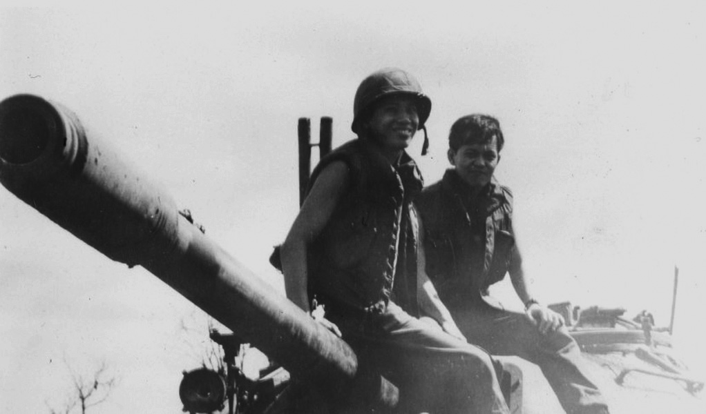 two people sitting on top of an old cannon