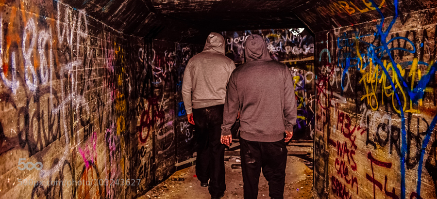 the couple walks together through a graffiti filled tunnel