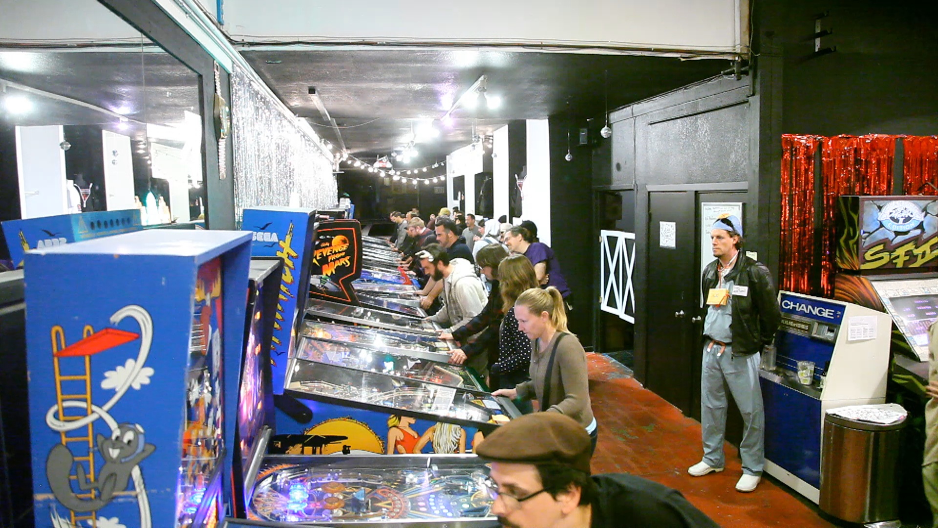 a group of people playing pinball games in an arcade