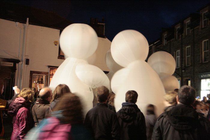 a crowd gathered to watch the white balloons being blown up