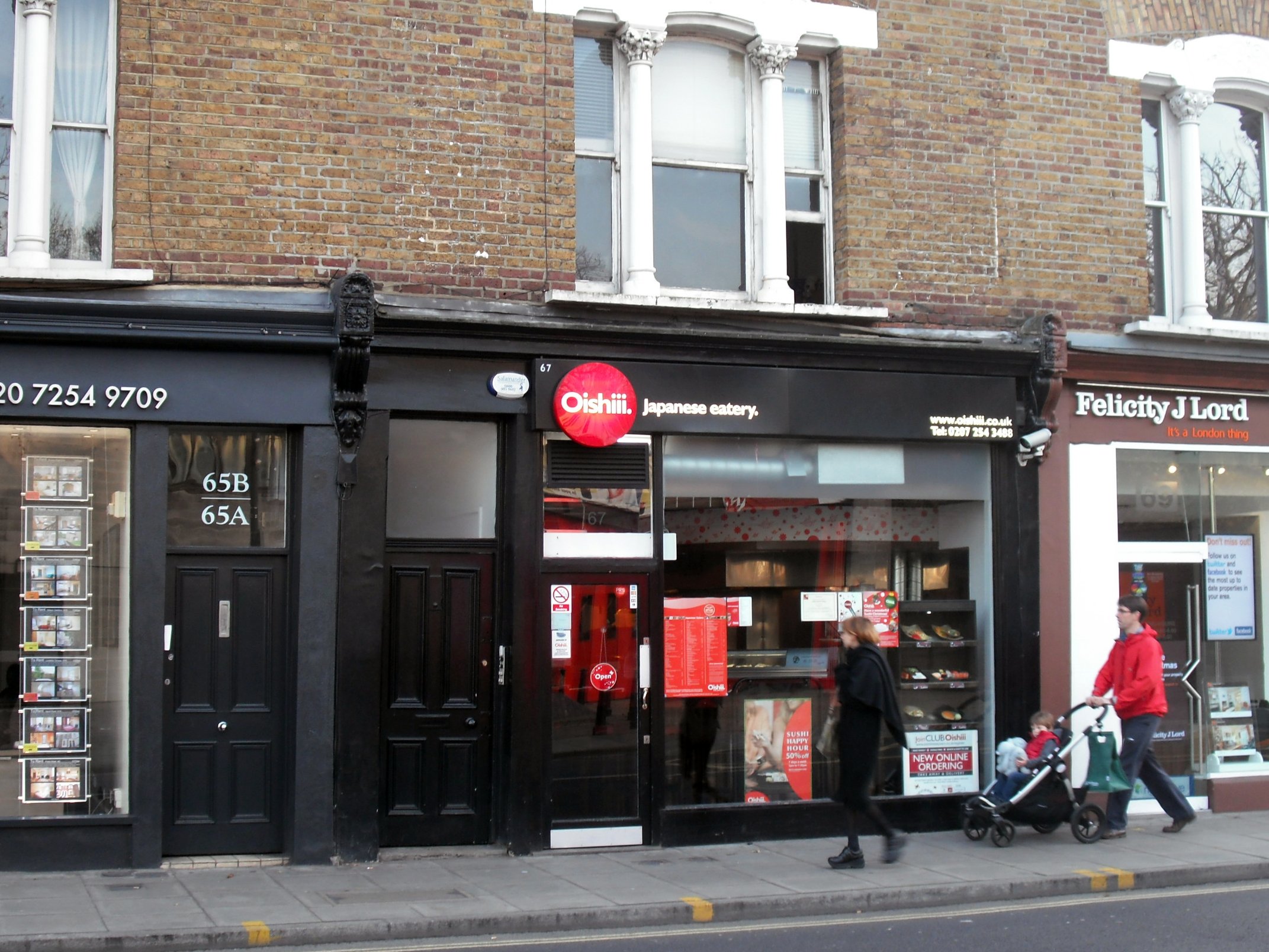 a woman hing a stroller down a street with shopping bags in front of store fronts