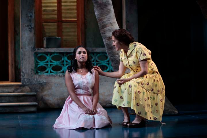 two women in dresses on stage next to a tree