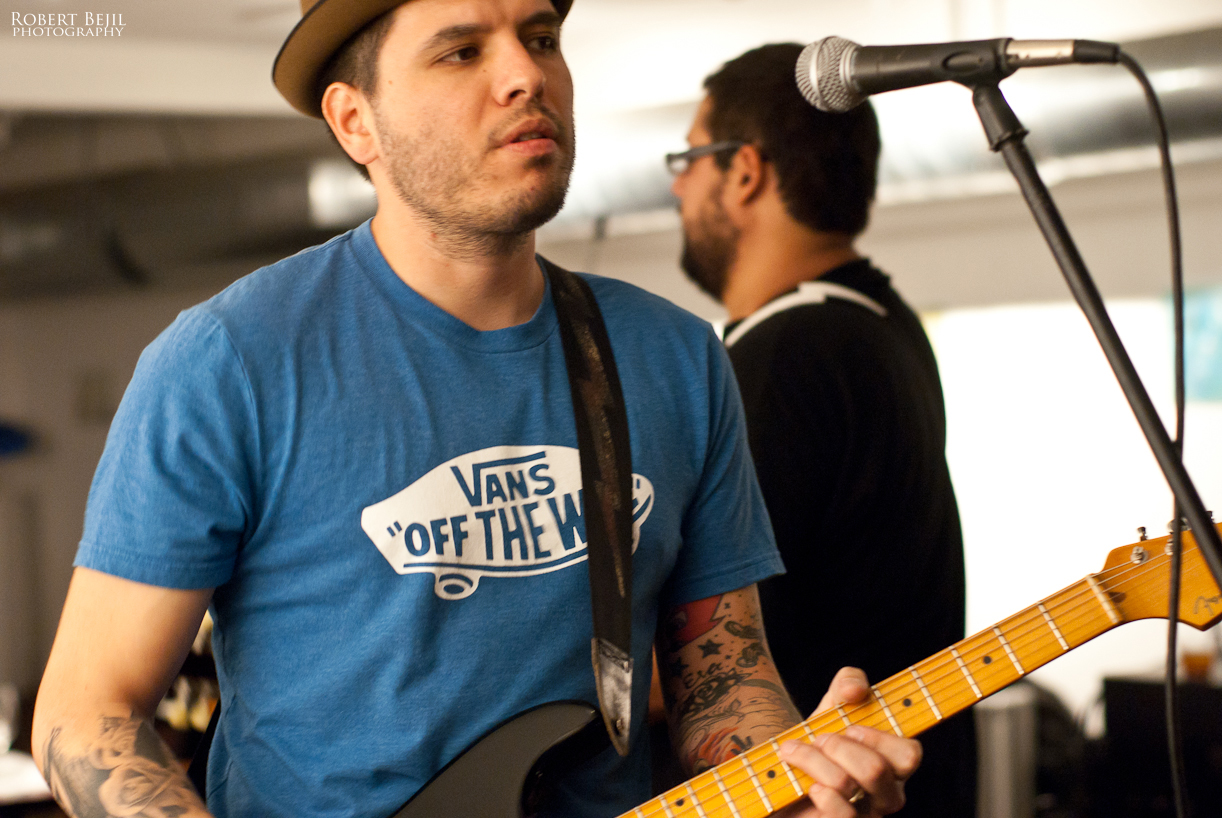 a man with tattooed arms playing guitar in front of microphone
