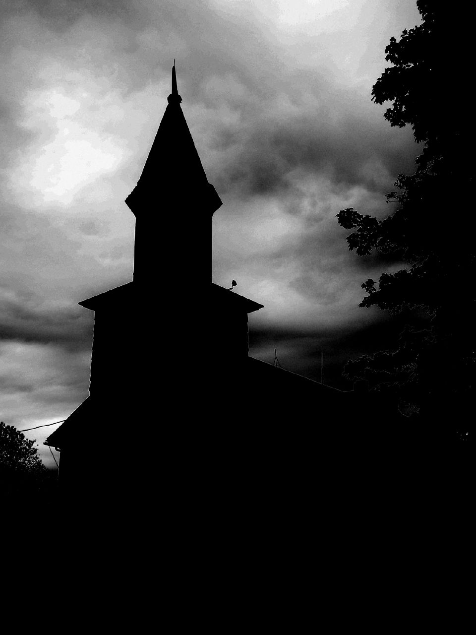 black and white po of a church spire with dark skies behind