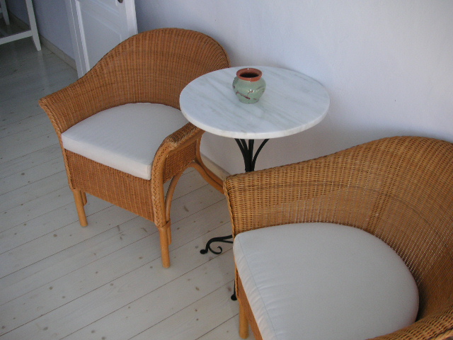 two wicker chairs sitting next to each other with a small white table