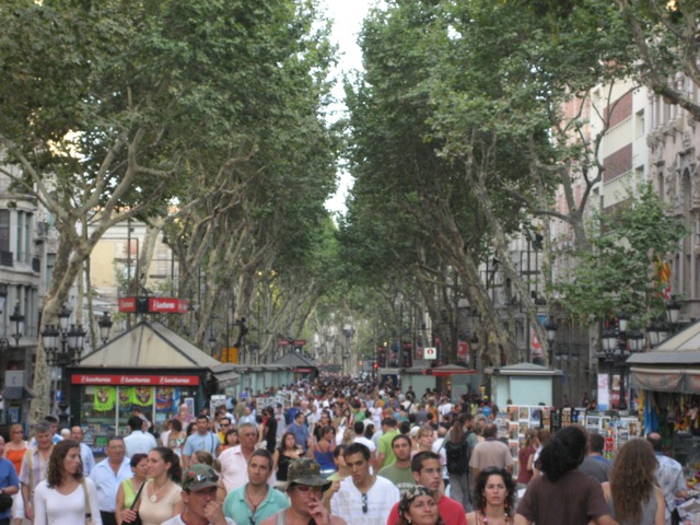 a very crowded street with people and lots of trees