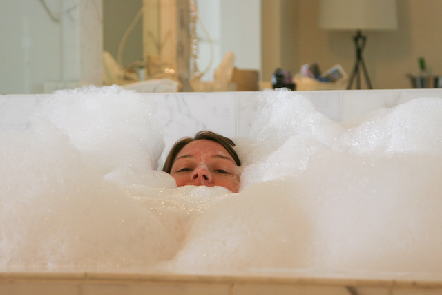a woman sleeping inside of a bubbley bathtub