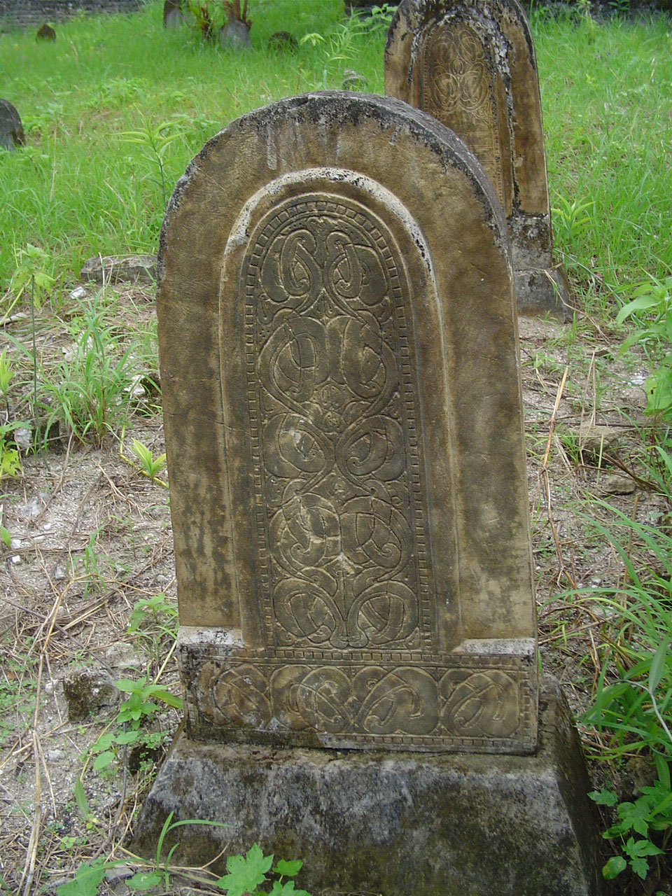 a stone marker in a grassy area with some plants