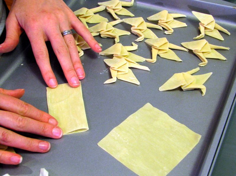 a person making origami on a tray with their hands