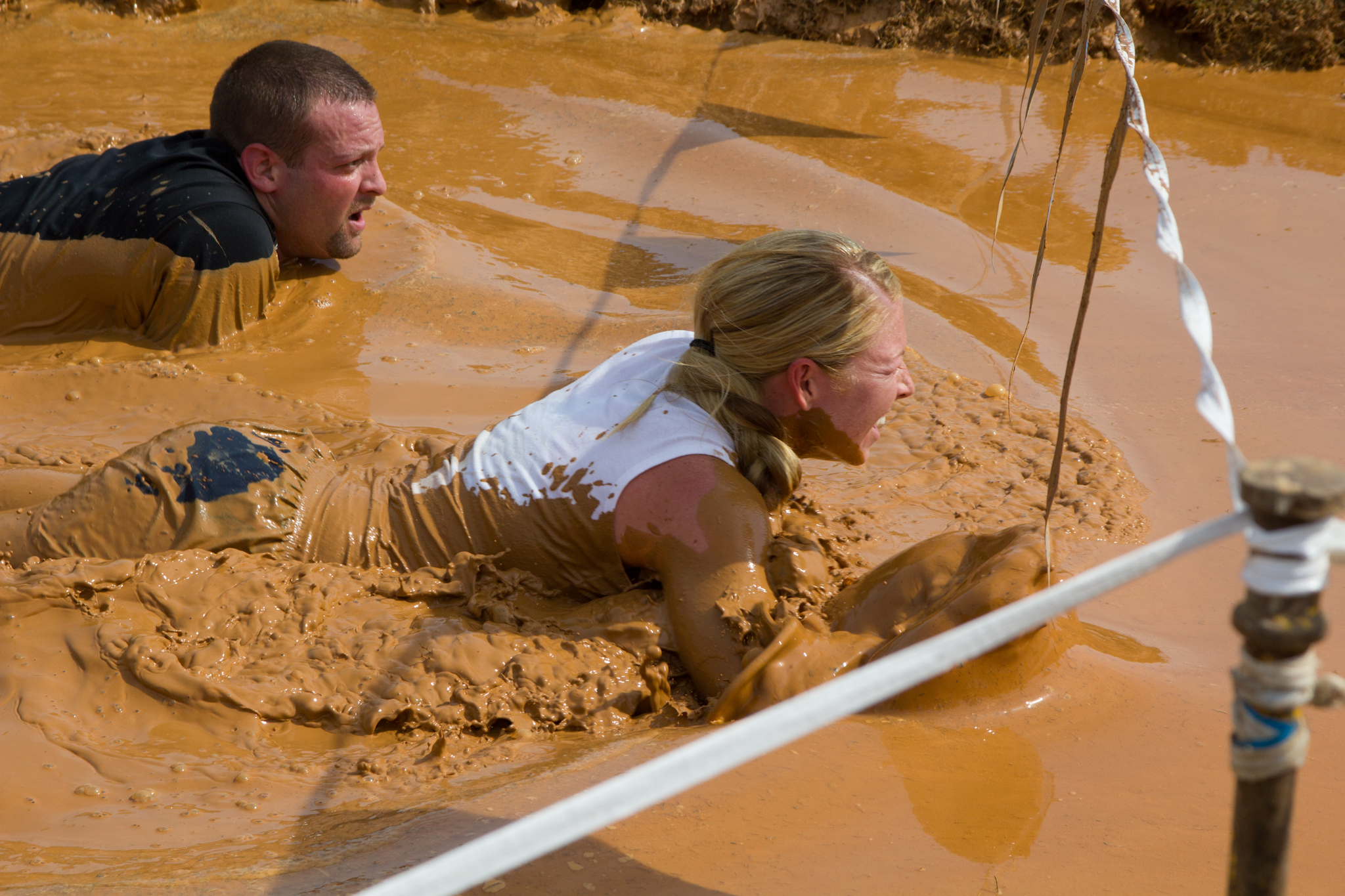 two people playing in a muddy area of water