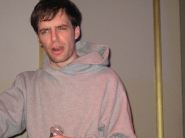 man in grey sweatshirt taking selfie while holding glass
