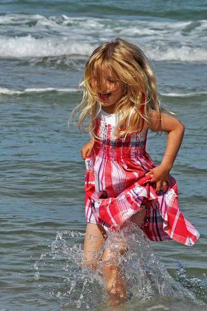 a little girl plays in the waves at the beach