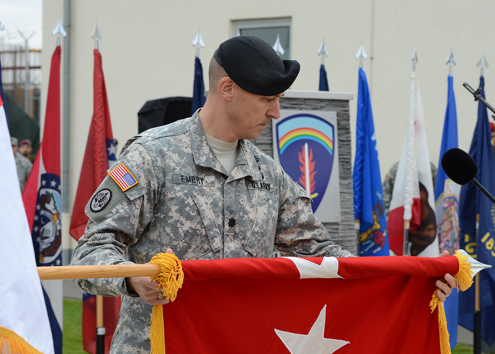 a soldier is holding a flag in front of microphones