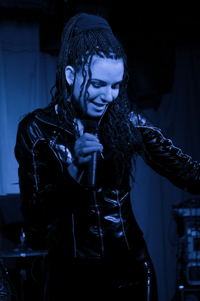 a male in a black leather outfit holding a microphone