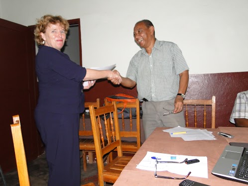 woman in blue blouse shaking hands with a man in gray shirt at table