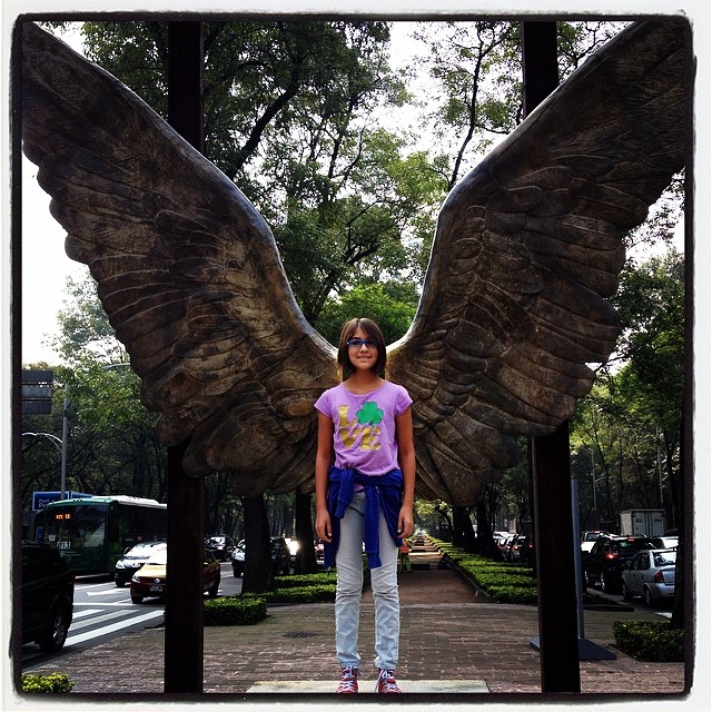 a girl standing in front of a sculpture of a big bird