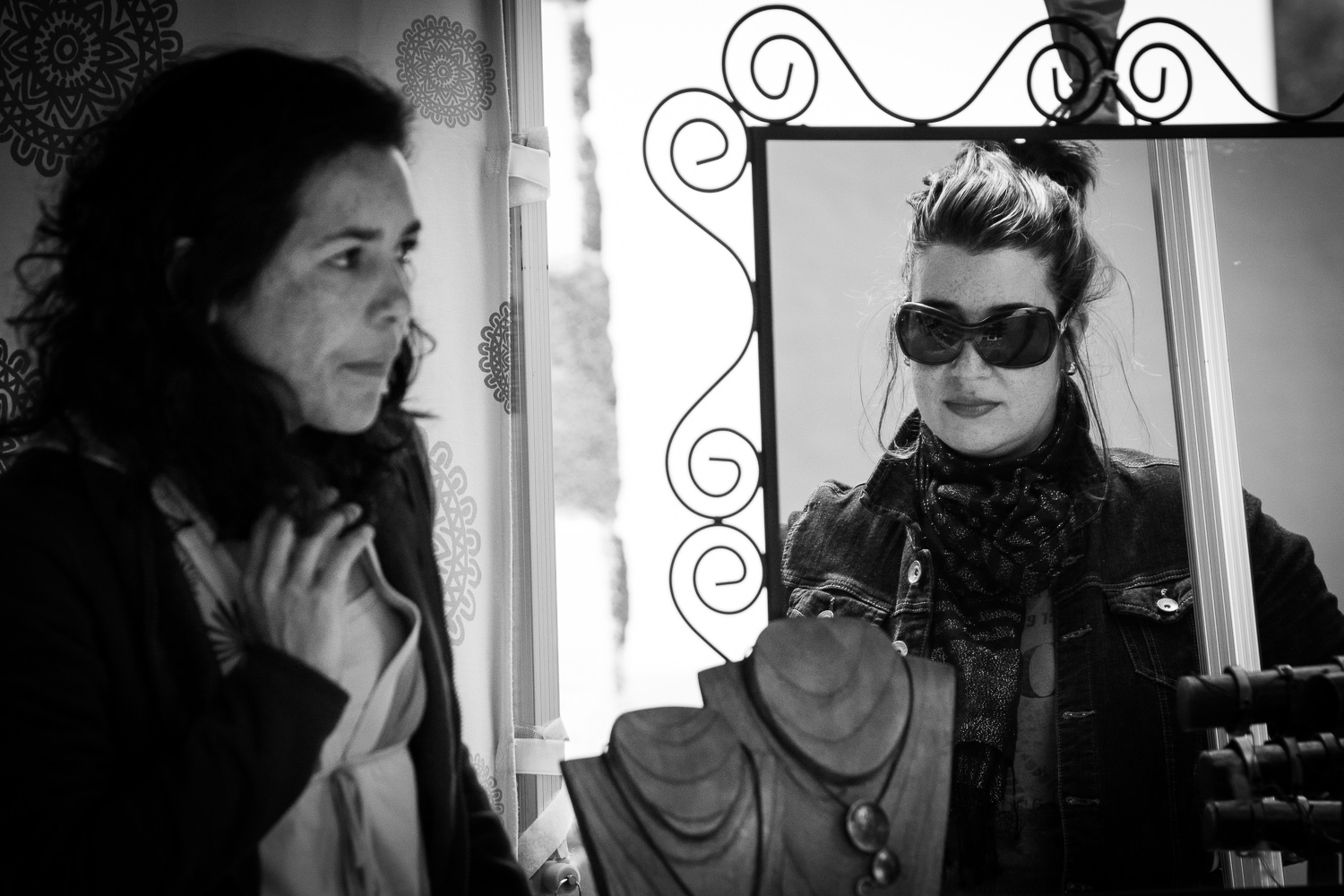 a woman with sunglasses looks into the mirror and smiles