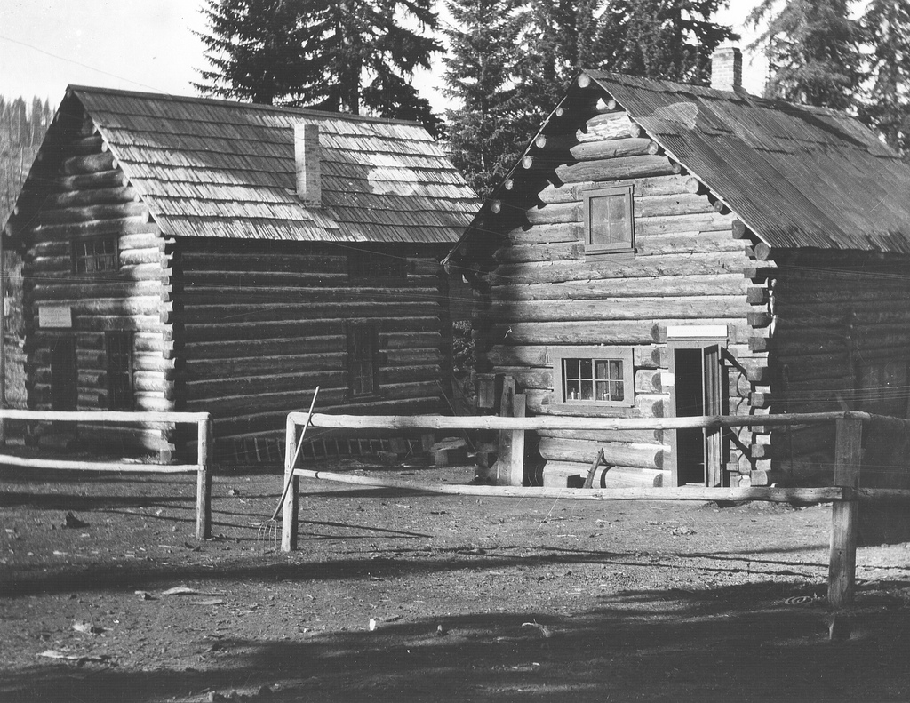 a black and white po of two old log cabins