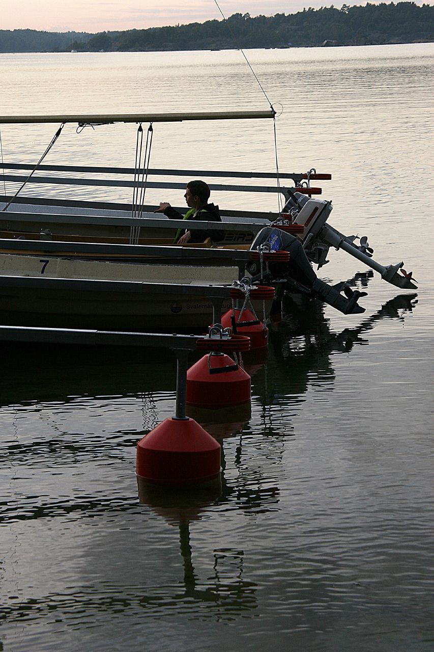 a row boat is pulled into the dock by three buoys