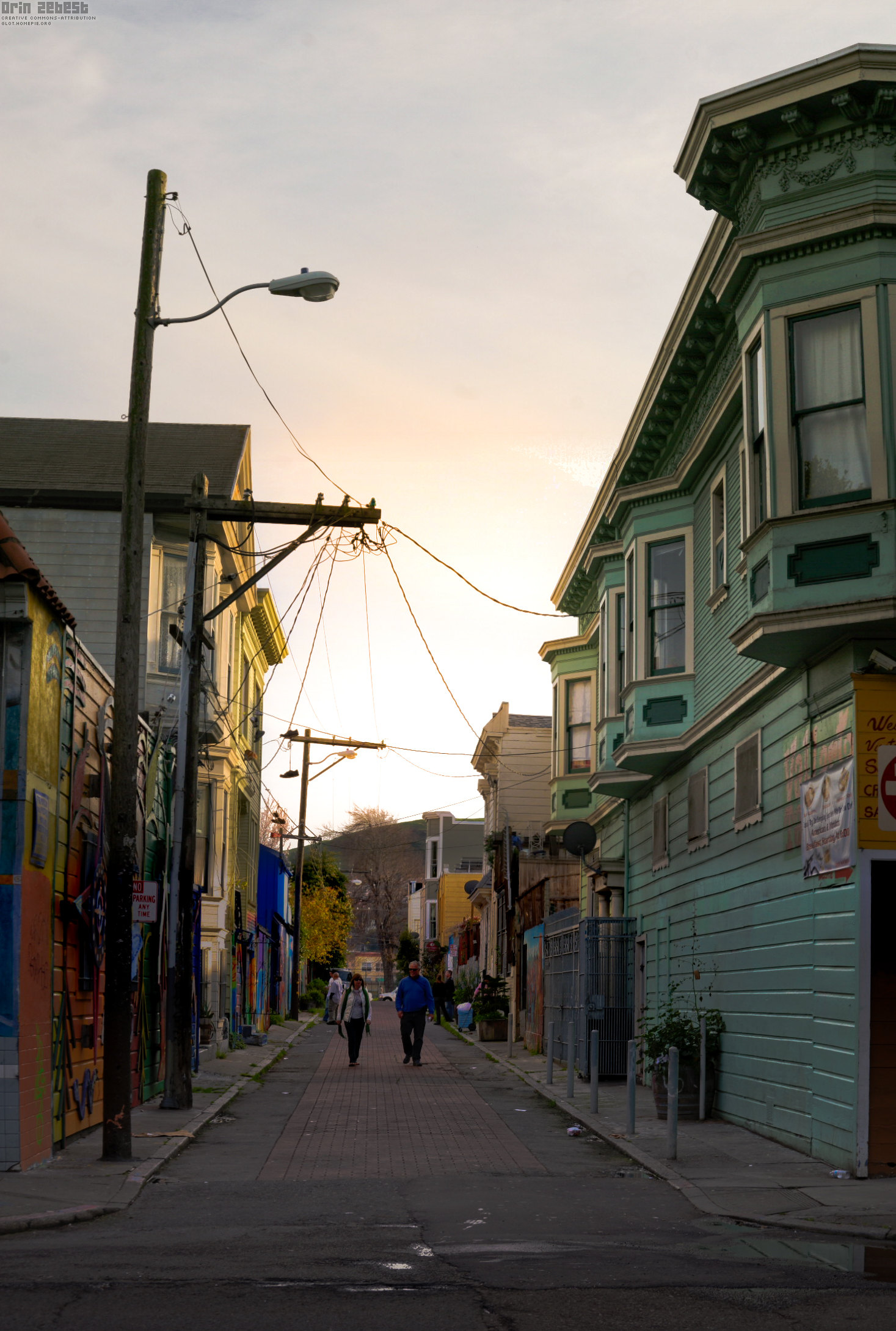 a couple of people walking down a road between houses