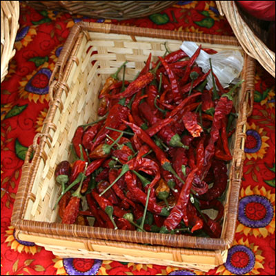 a basket filled with red chilli peppers in front of some baskets
