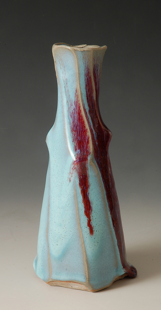 a blue vase with red dripping paint on it