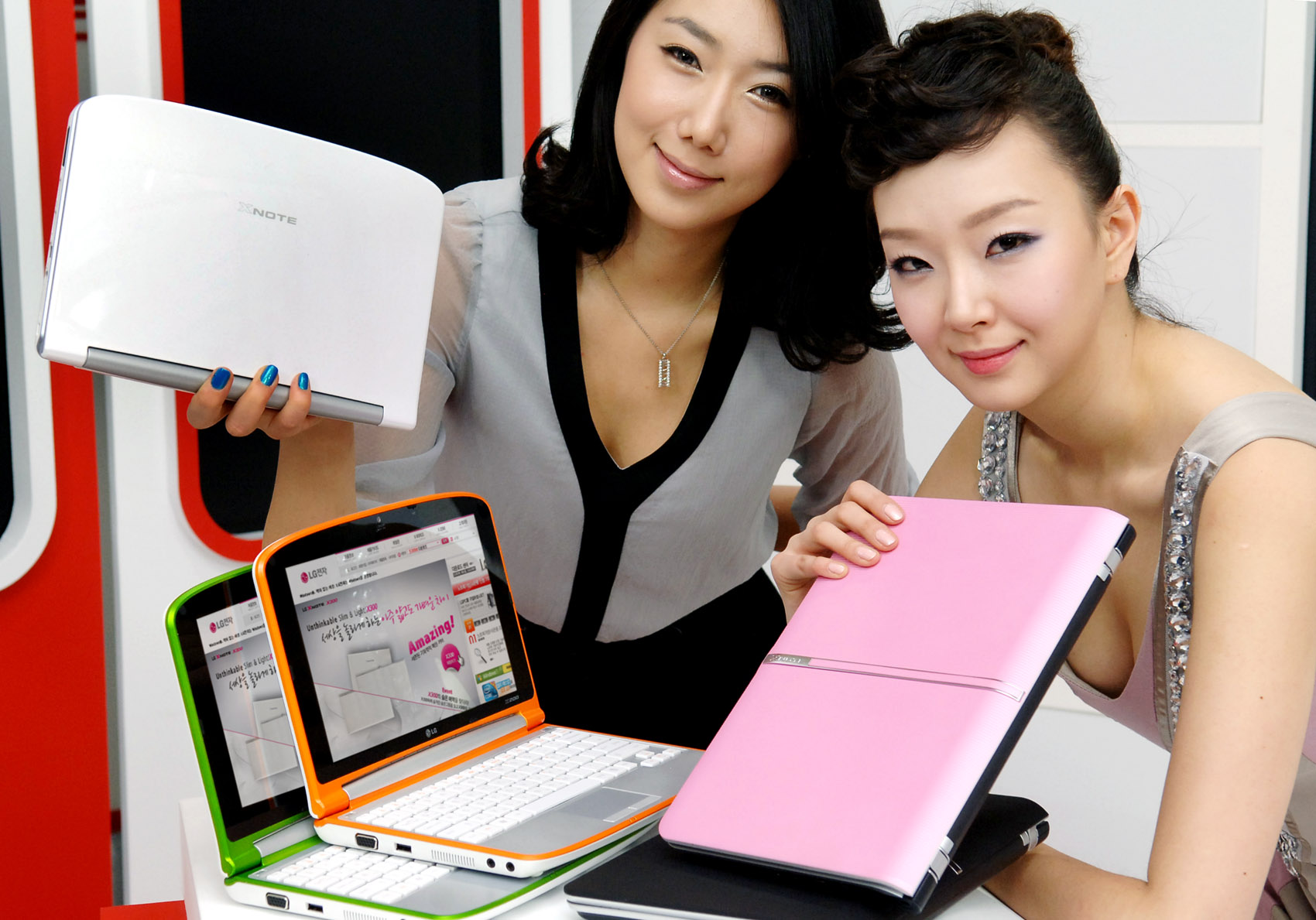 two ladies are holding up the pink laptop