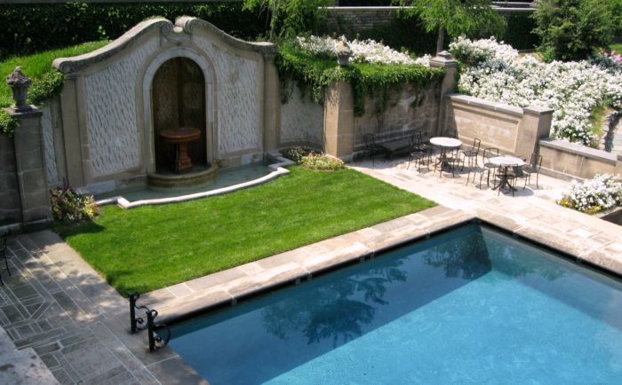 a pool in a backyard that has a patio and a lawn