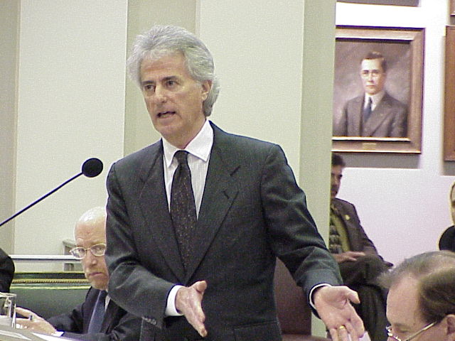 a man is in a suit and tie speaking at a podium