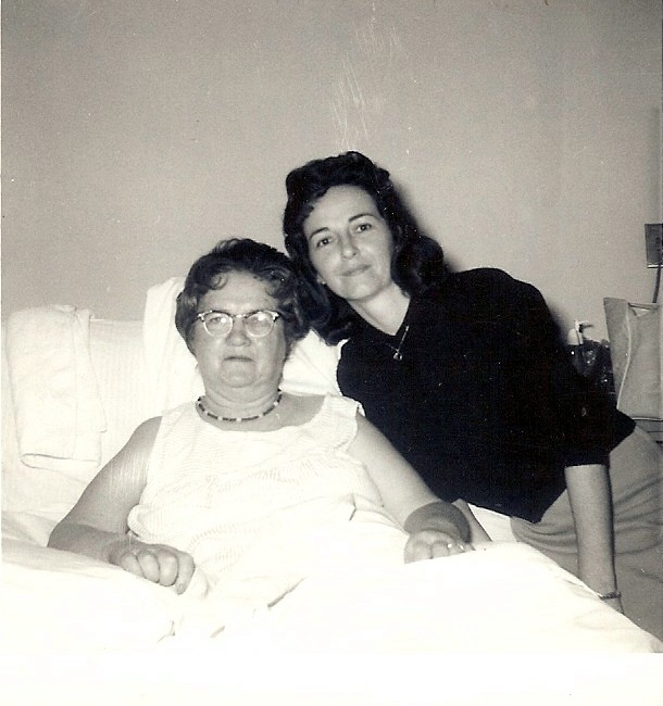 a woman in a black shirt is sitting on a bed with a friend