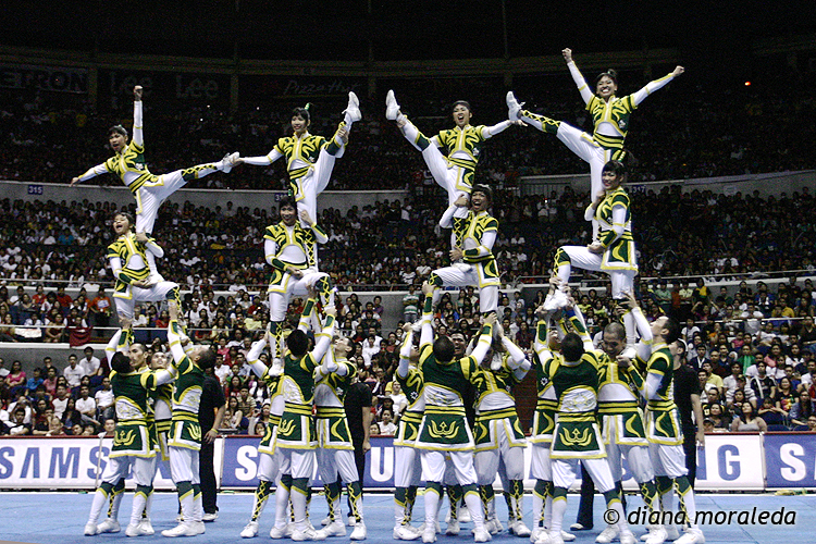 cheer team in white and green outfits performing stunts at event