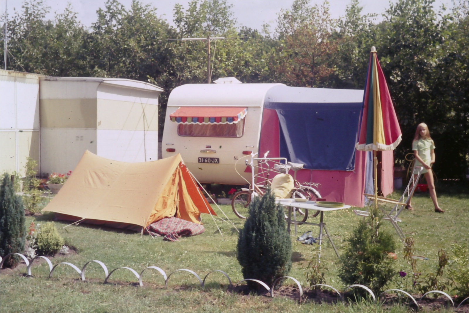 the tent is set up in a yard outside a camper
